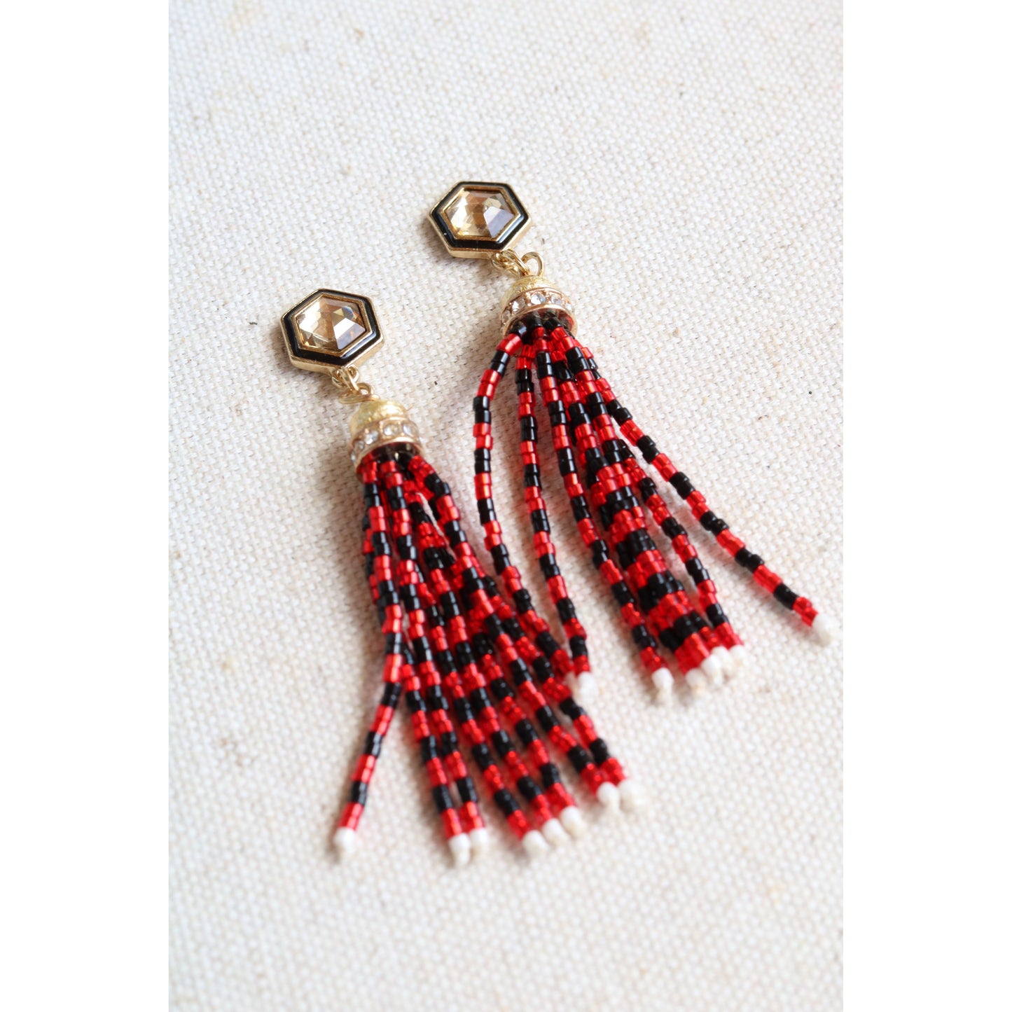Red and black beaded tassel earrings on a white background