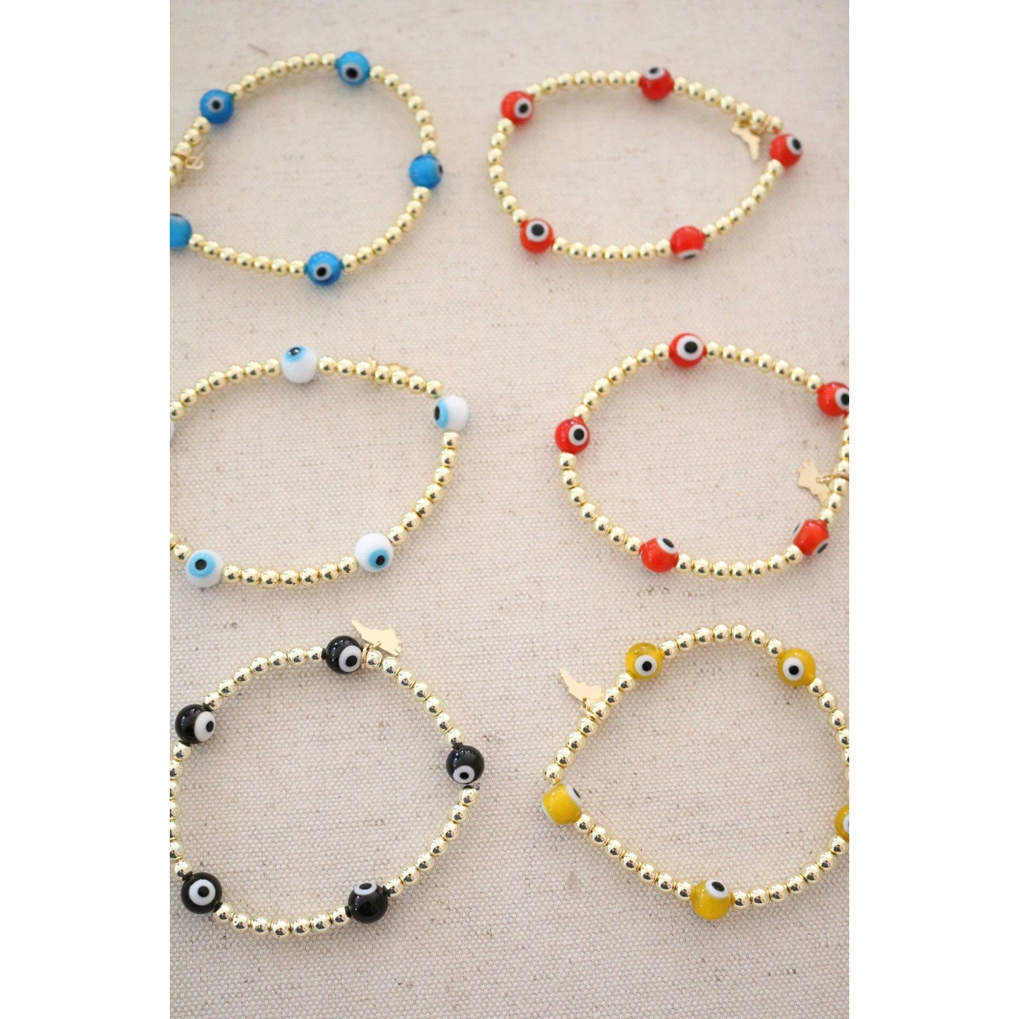the evil eye goldie bracelet shown in blue, orange,white, red, yellow, and black color options