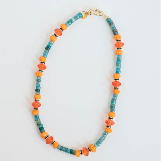 necklace with blue, turquoise, and orange beads and a gold pave clasp on a light background