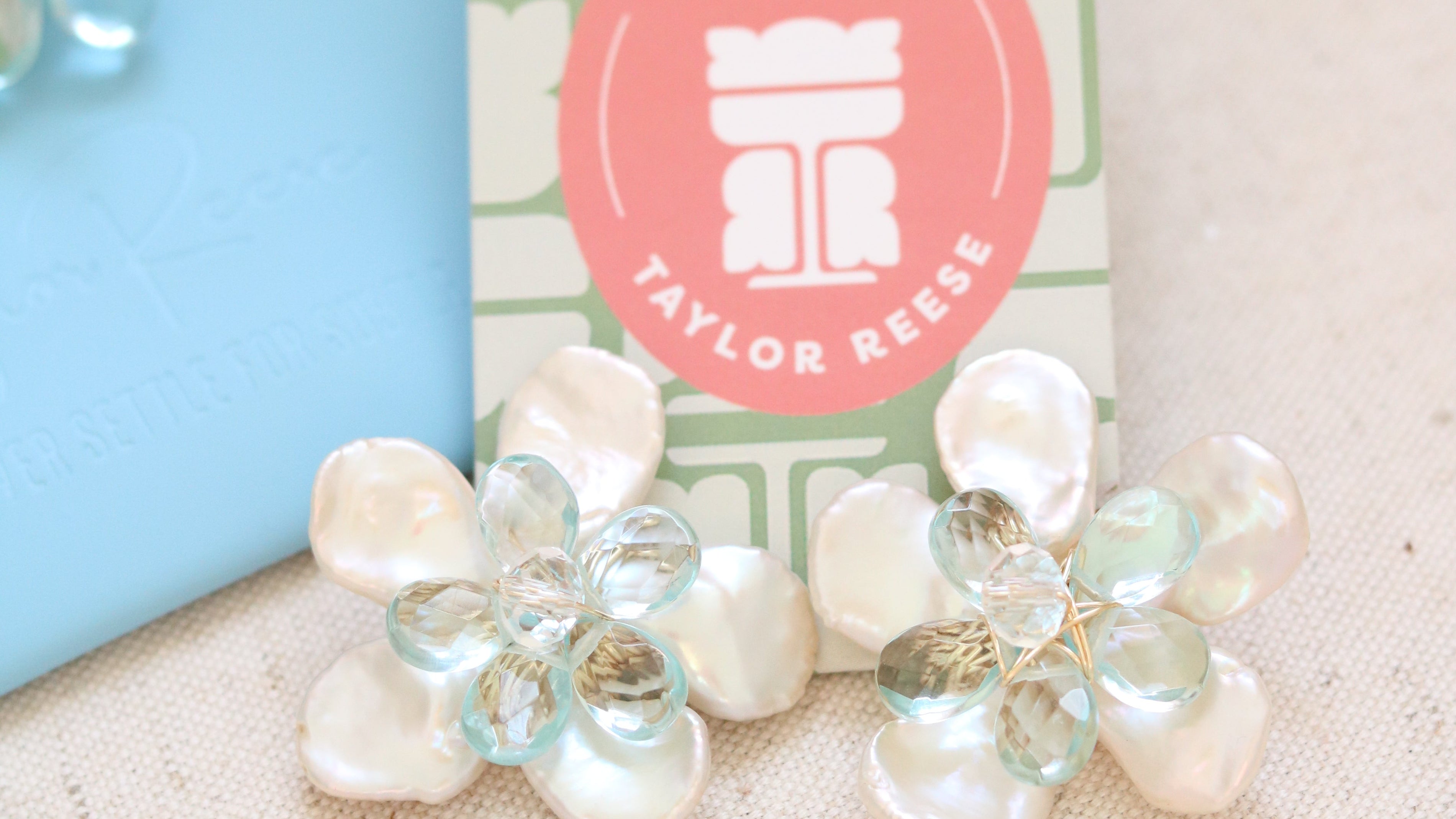 Handcrafted custom bridal earrings made in North Carolina featuring mother of pearl petals and blue quartz stones, designed for a beach wedding.