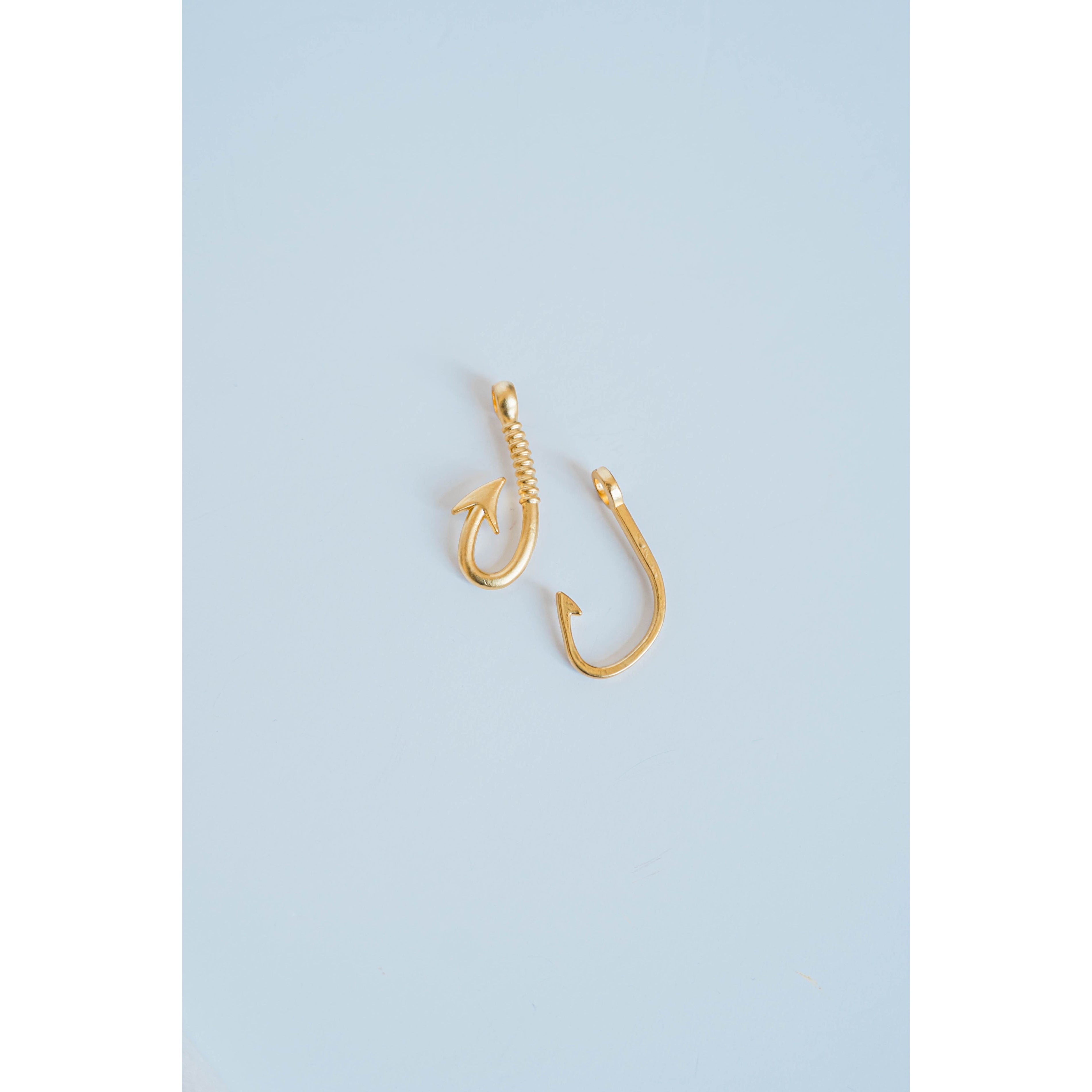two gold fishing hook charms on a light grey background