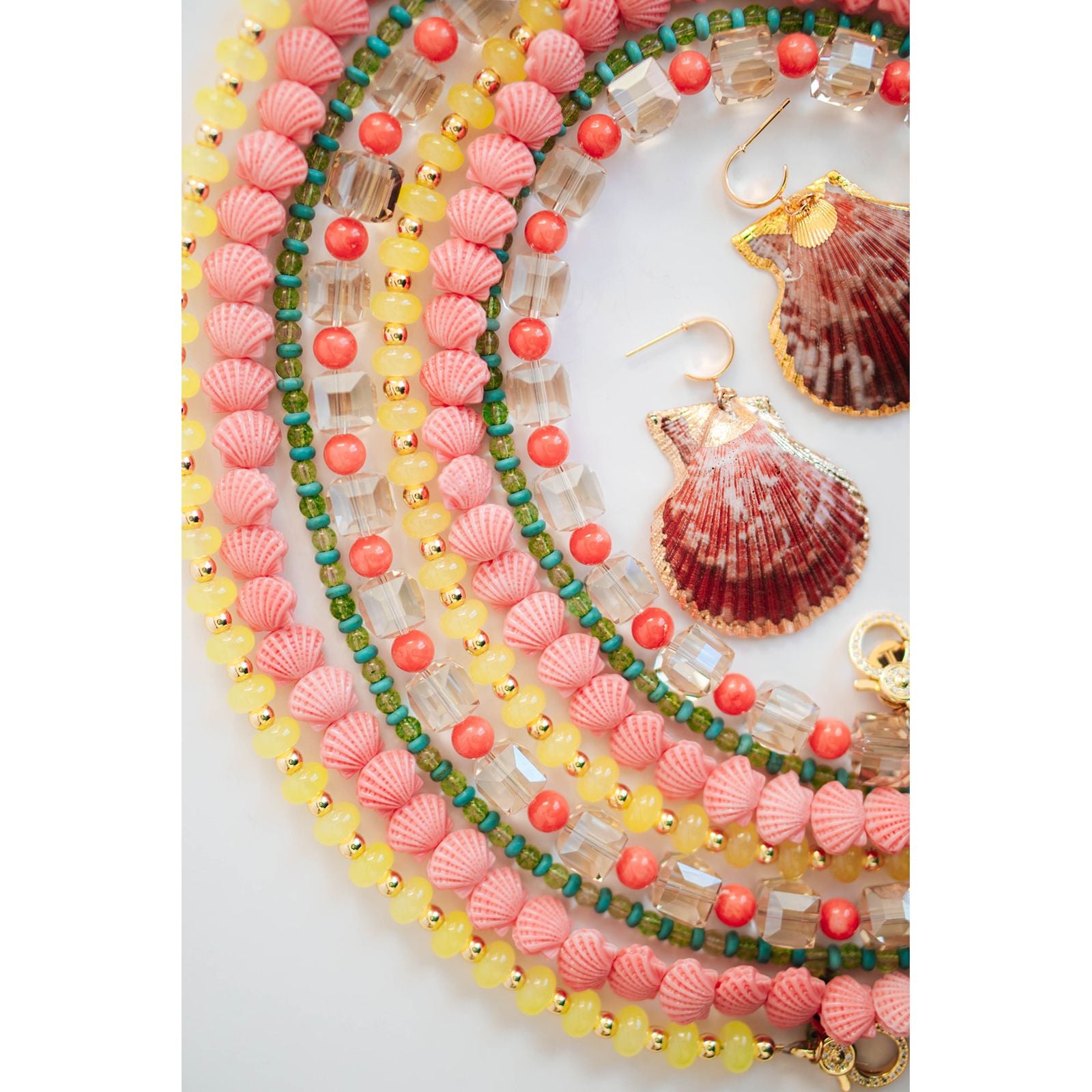 Colorful beaded necklaces and shell earrings on a white background