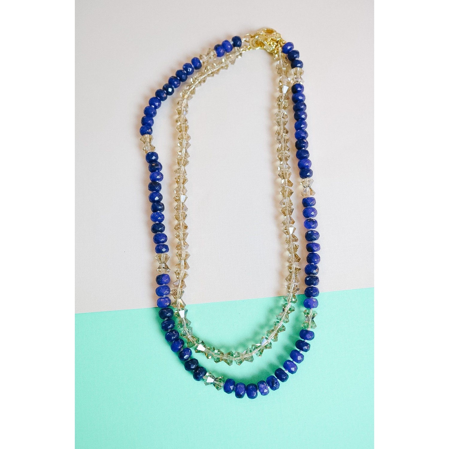 The crystal bow necklace shown, styled with the lapis bow necklace