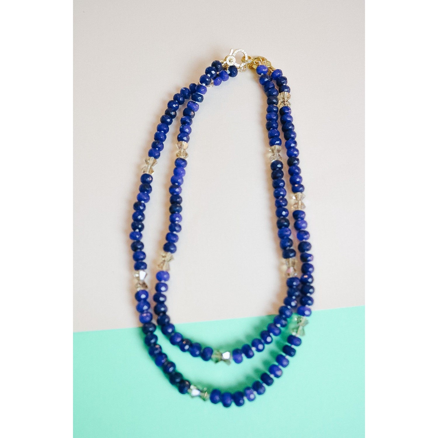 two lapis lazuli crystal bow necklaces shown styled, layered together.