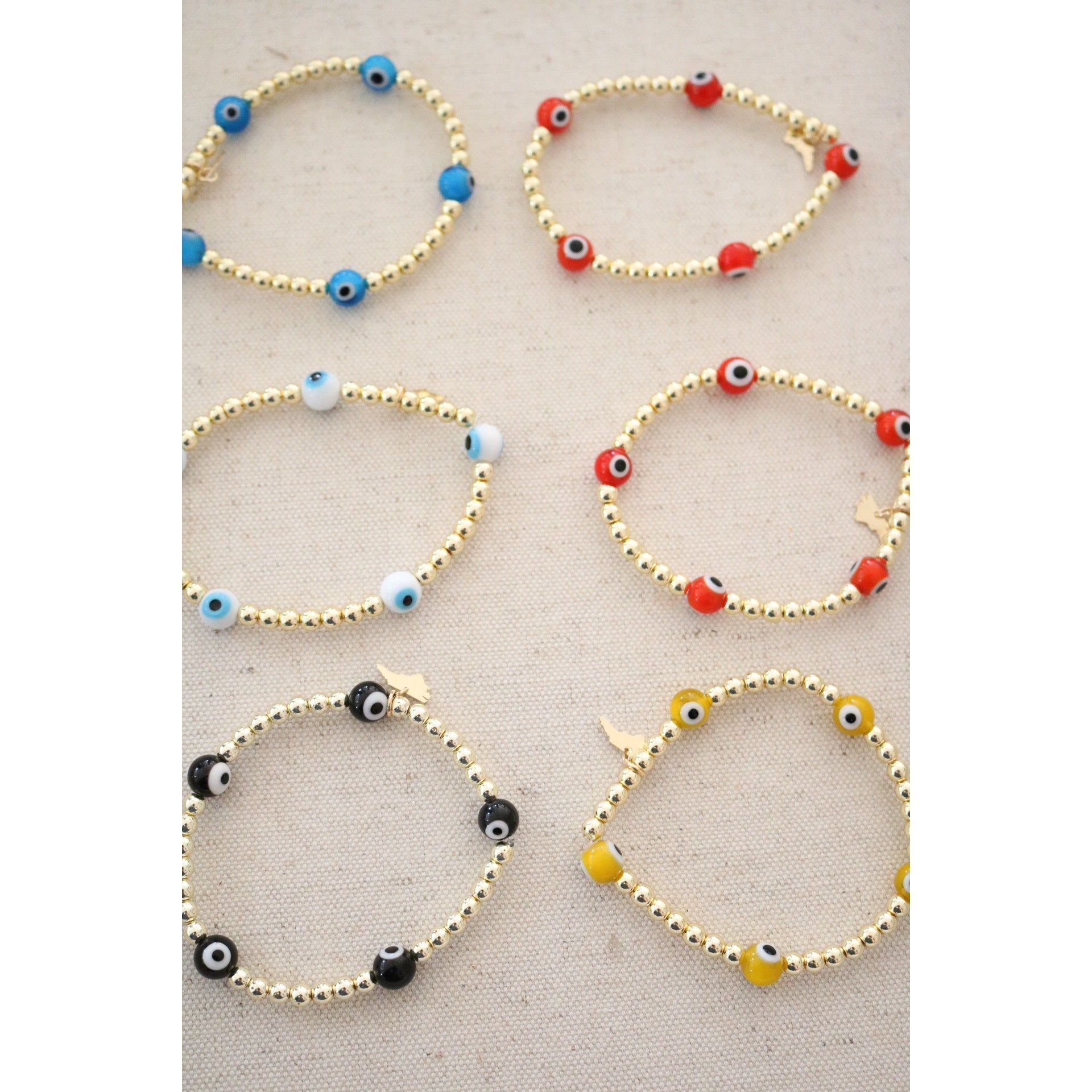 the evil eye goldie bracelet shown in blue, orange,white, red, yellow, and black color options