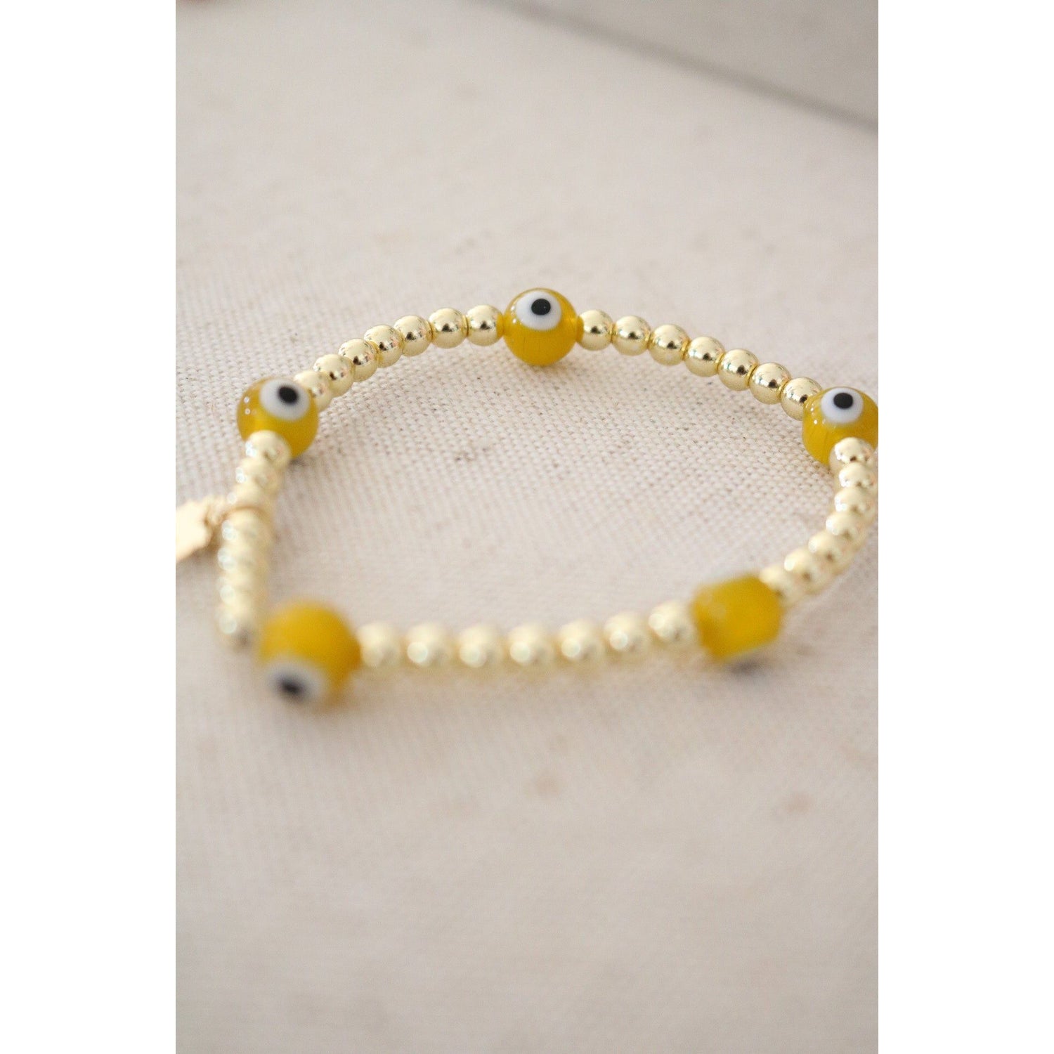 white and yellow evil eye beads on a gold hematite stretch bracelet