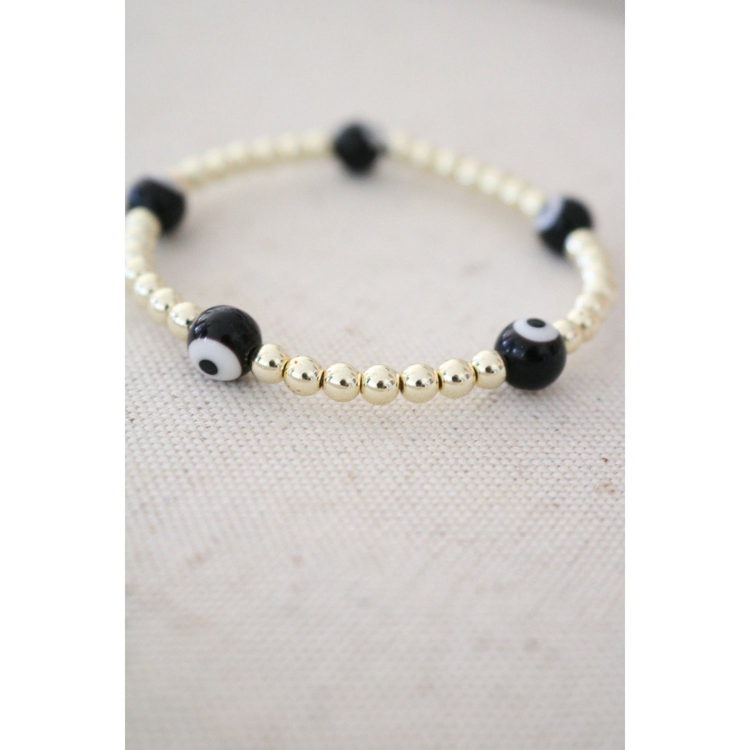 white and black evil eye beads on a gold hematite stretch bracelet