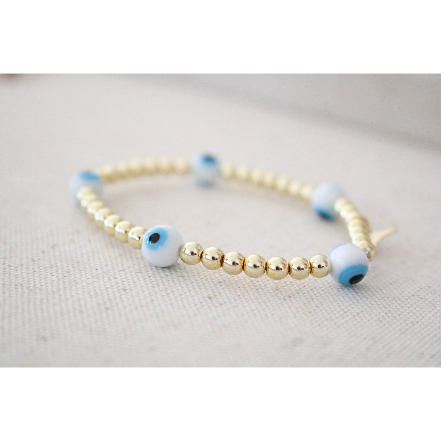 white and blue evil eye beads on a gold hematite stretch bracelet