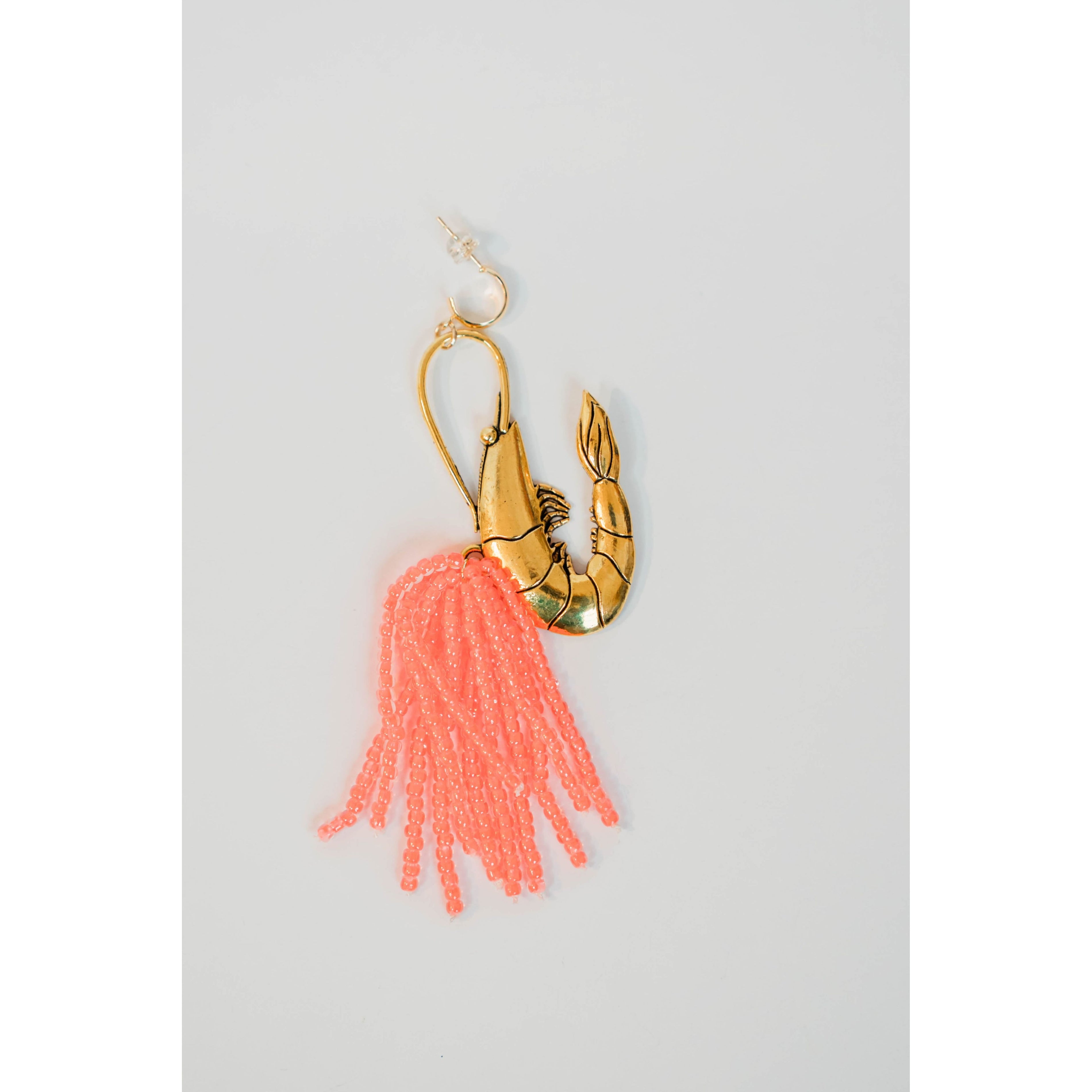 Gold shrimp earrings with pink beaded tassels on a light gray background