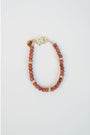 A bracelet with a pattern of goldstone and pavé beads are strung on cord with a pavé clasp and logo charm.