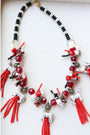 Red crystal beaded tassels are topped with ceramic wolf beads on a red and black beaded necklace with pave clasp. 