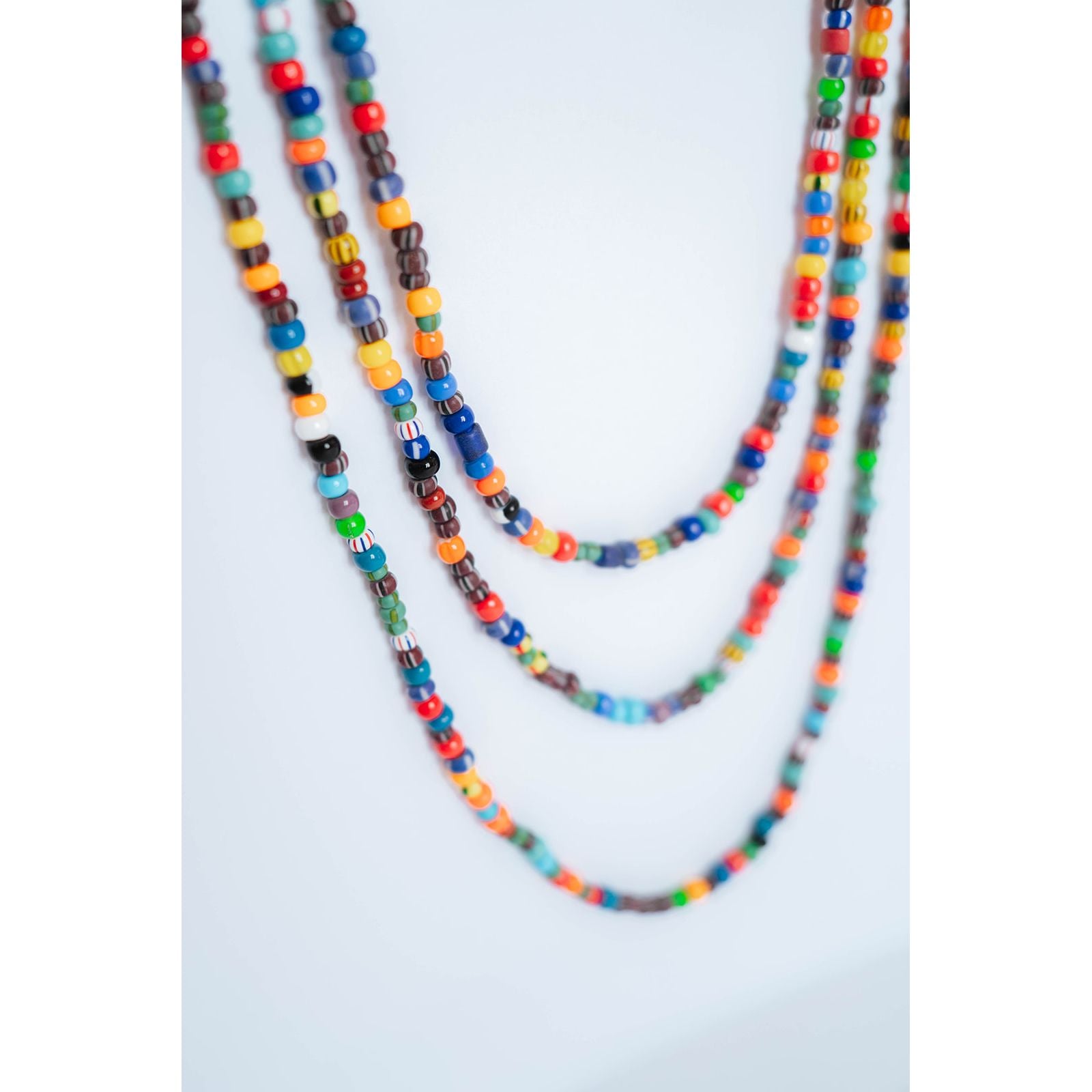 close-up shot of 3 layered multicolor beaded necklaces on a light background