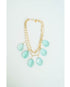 Gold layered chain necklace with aqua colored teardrop pendants on a light grey background