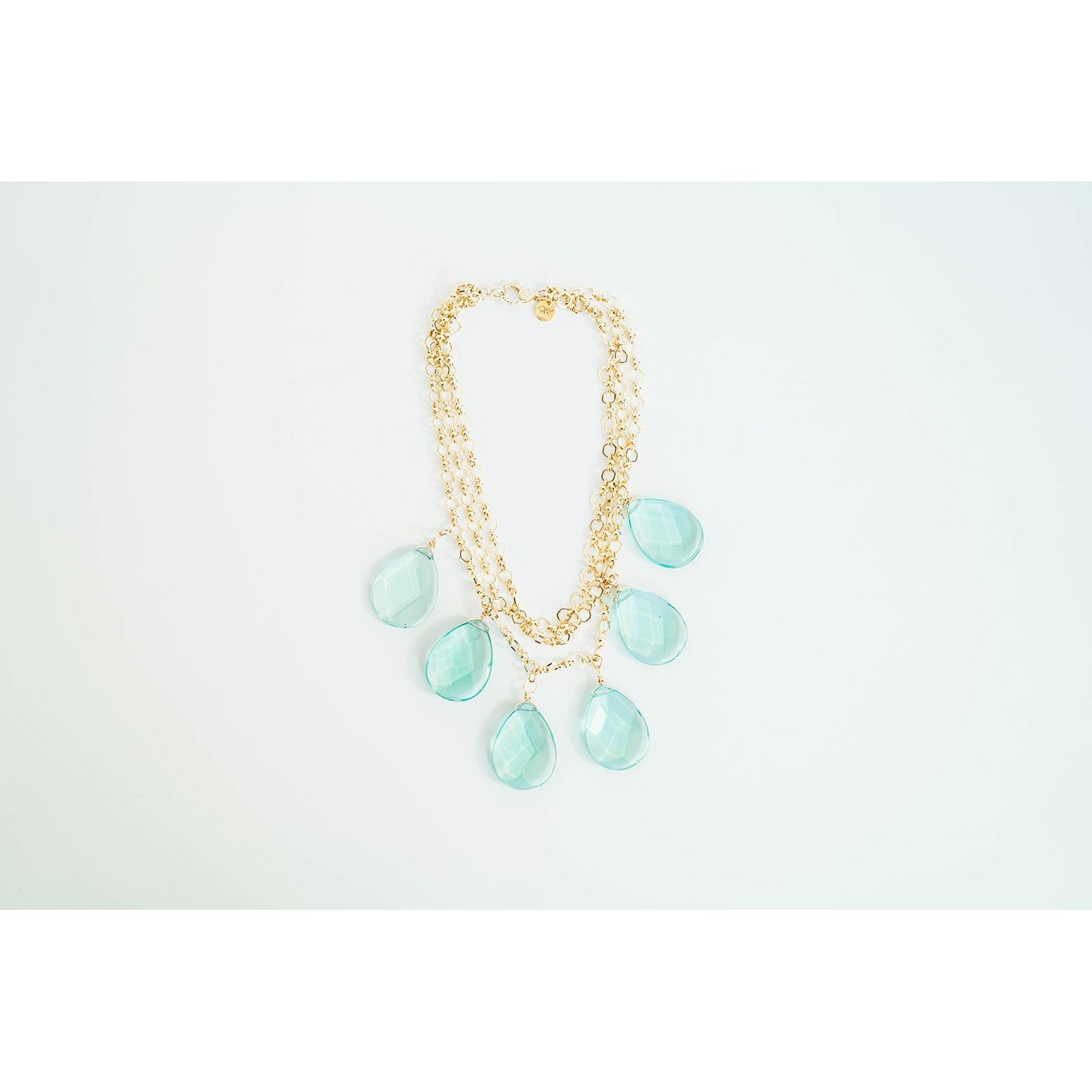 Gold layered chain necklace with teal teardrop pendants on a light grey background