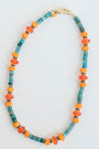 necklace with blue, turquoise, and orange beads and a gold pave clasp on a light background