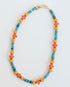 necklace with blue, turquoise, and orange beads and a gold pave clasp on a light background