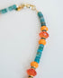 necklace with blue, turquoise, orange beads and black and gold pave spacers on a light background