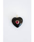 black heart-shaped pendant with a red center crystal gemstone on a light background