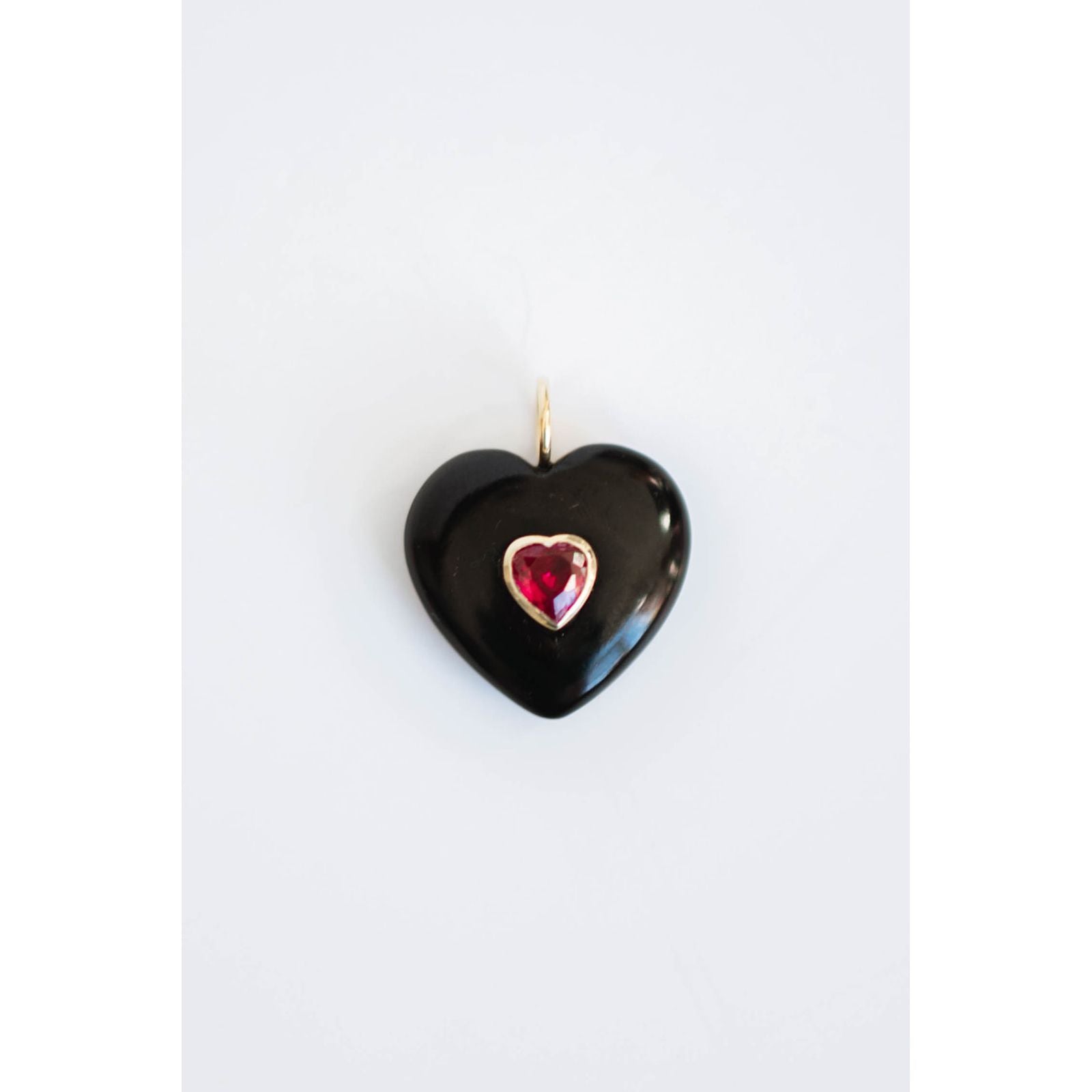 black heart-shaped pendant with a red center crystal gemstone on a light background