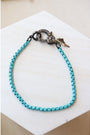 light blue box chain bracelet with a pave gunmetal lever clasp on a white background