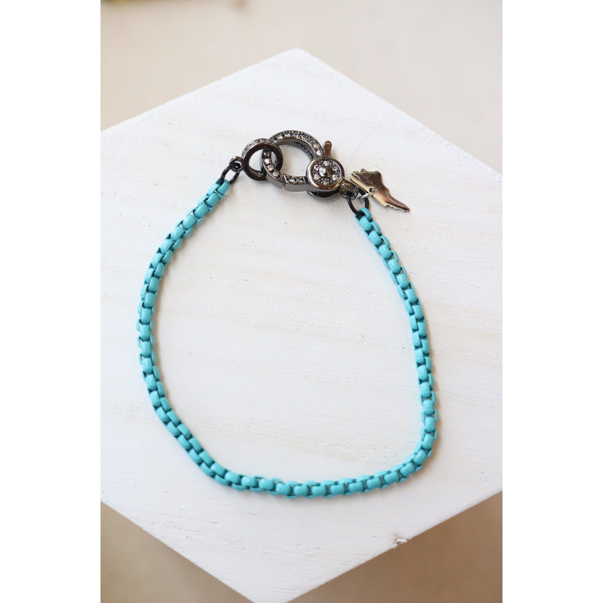 light blue box chain bracelet with a pave gunmetal lever clasp on a white background
