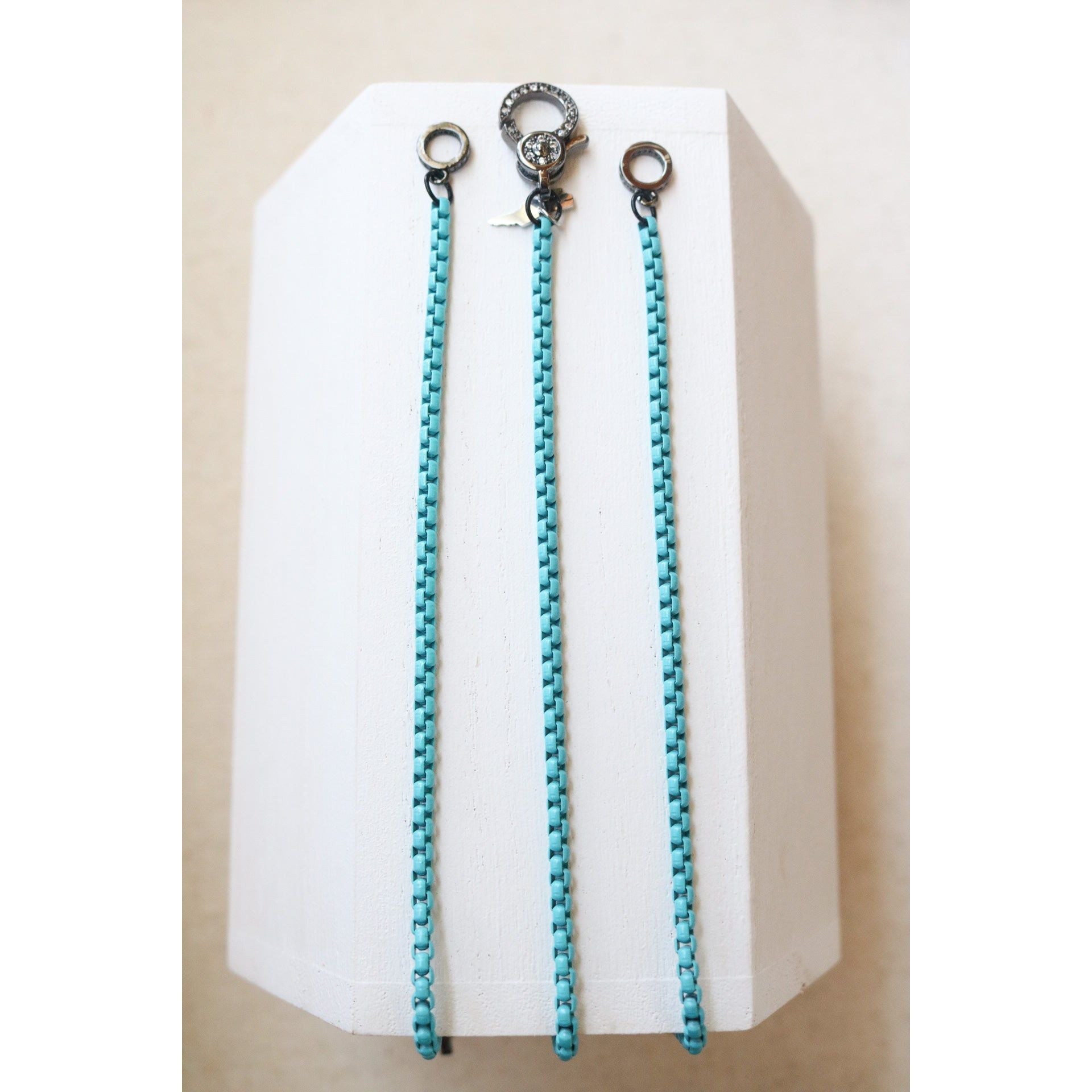 set of 3 light blue box chain bracelets with a gunmetal pave lever clasp on a white background