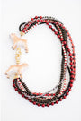 statement necklace with layered strands of red, black, and gold beads and two dog pendants with a gold pave clasp on a white background