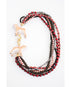 statement necklace with layered strands of red, black, and gold beads and two dog pendants with a gold pave clasp on a white background