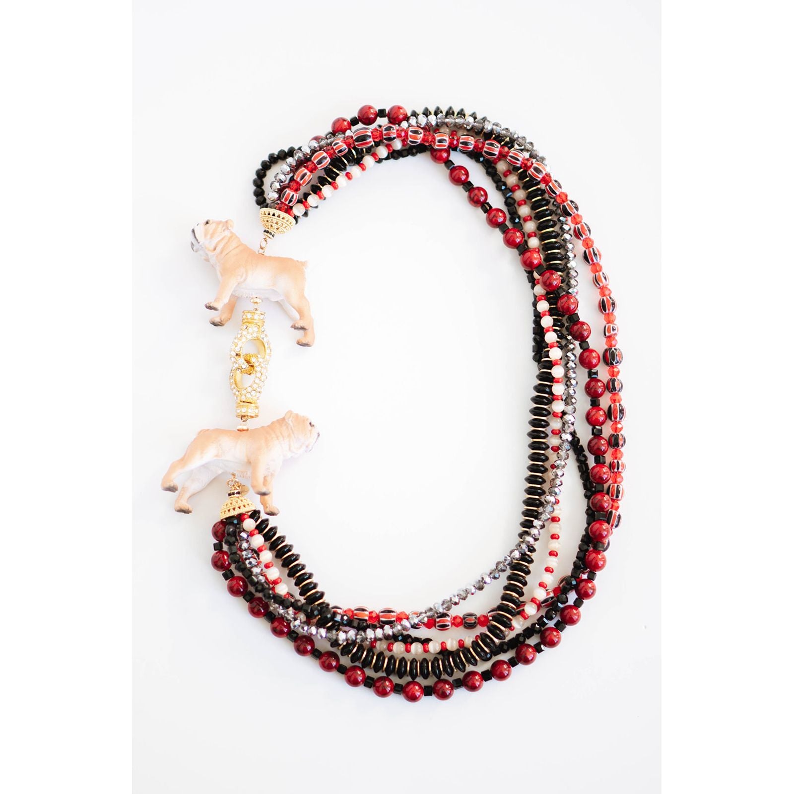 statement necklace with layered strands of red, black, and gold beads and two dog pendants with a gold pave clasp on a white background