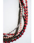 stack of various red, black, and gold beaded necklaces on a light background