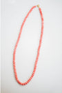 coral pink shell beaded necklace on a light gray background