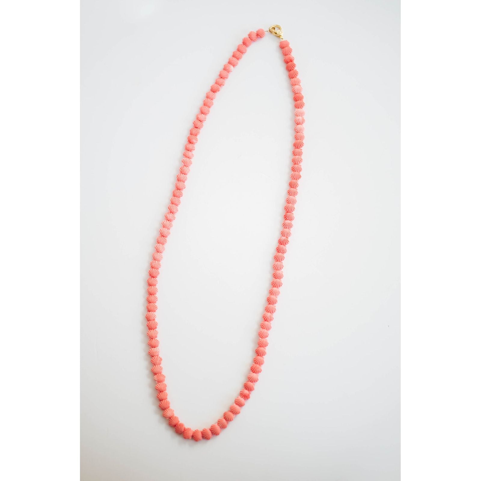 coral pink shell beaded necklace on a light gray background