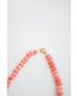 Necklace with pink shell-like beads with gold pave clasp on a light gray background