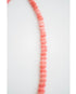 Necklace with coral pink shell-like beads on a white background