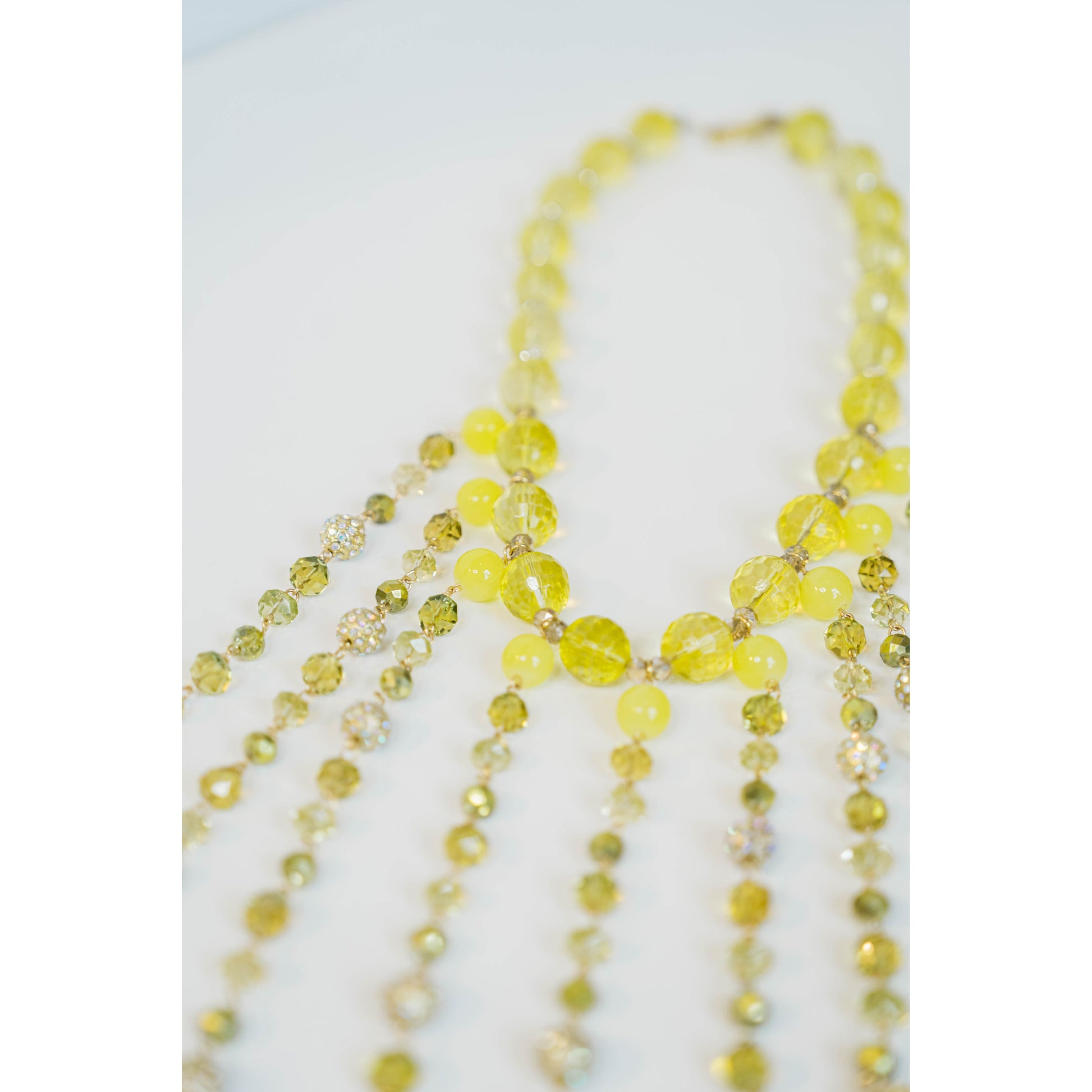 beaded necklace with yellow toned crystal bead accents on a light grey background