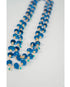 Long beaded necklace with crystal blue and turquoise and gold chain on a light gray background