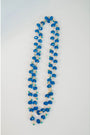 Long beaded necklace with crystal blue and turquoise and gold chain on a light gray background