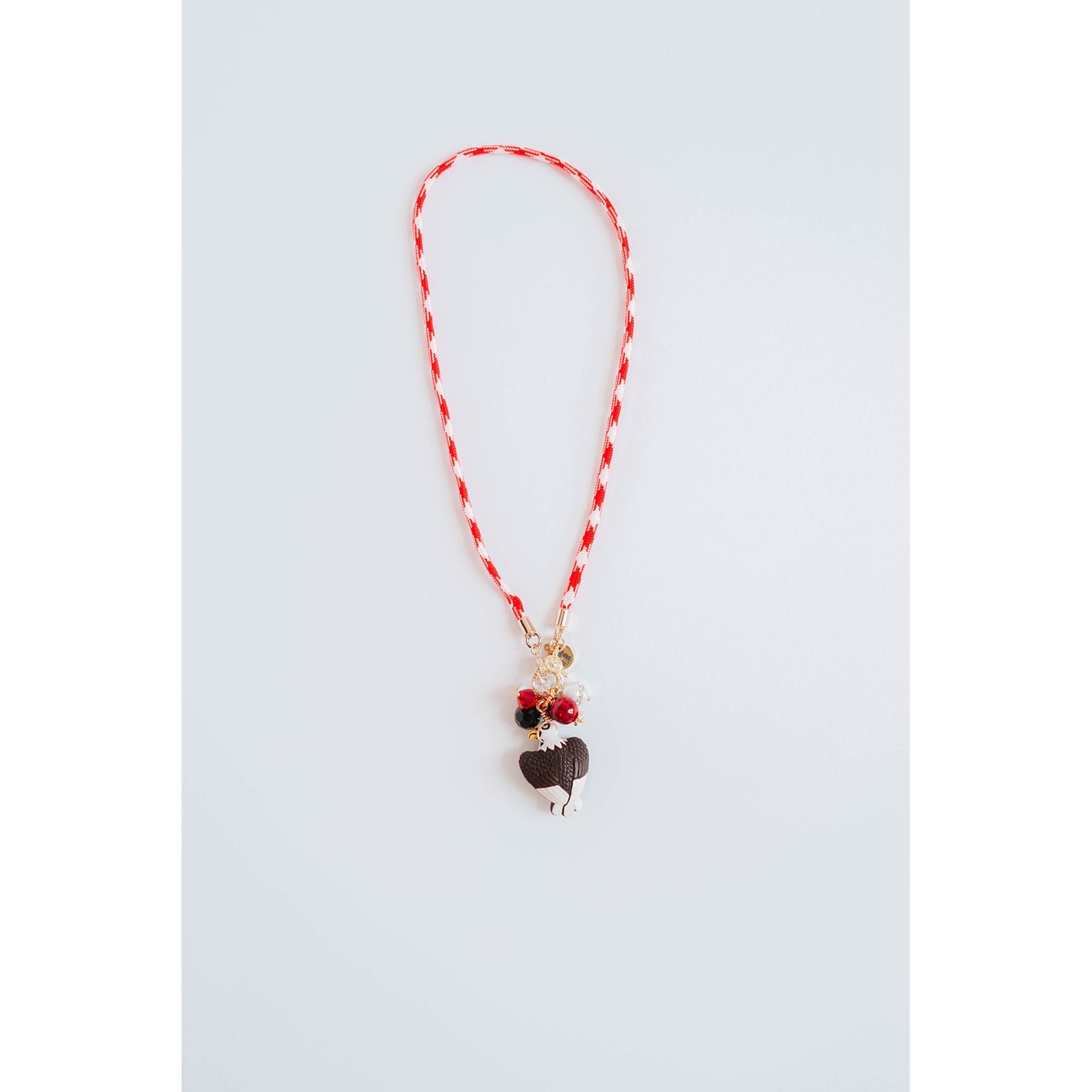 red and white color block cord necklace with a gold pave charm and an eagle pendant with black and red bead accents