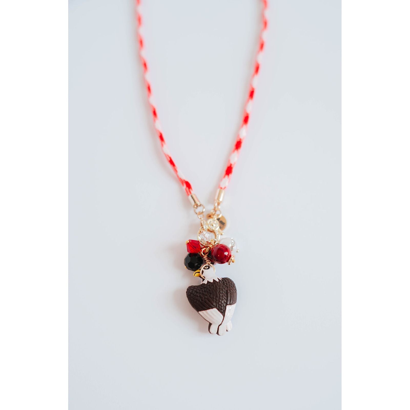 red and white color block cord necklace with a gold pave charm and an eagle pendant with black and red bead accents