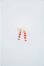 Pair of red and gold fish-shaped earrings on a light gray background
