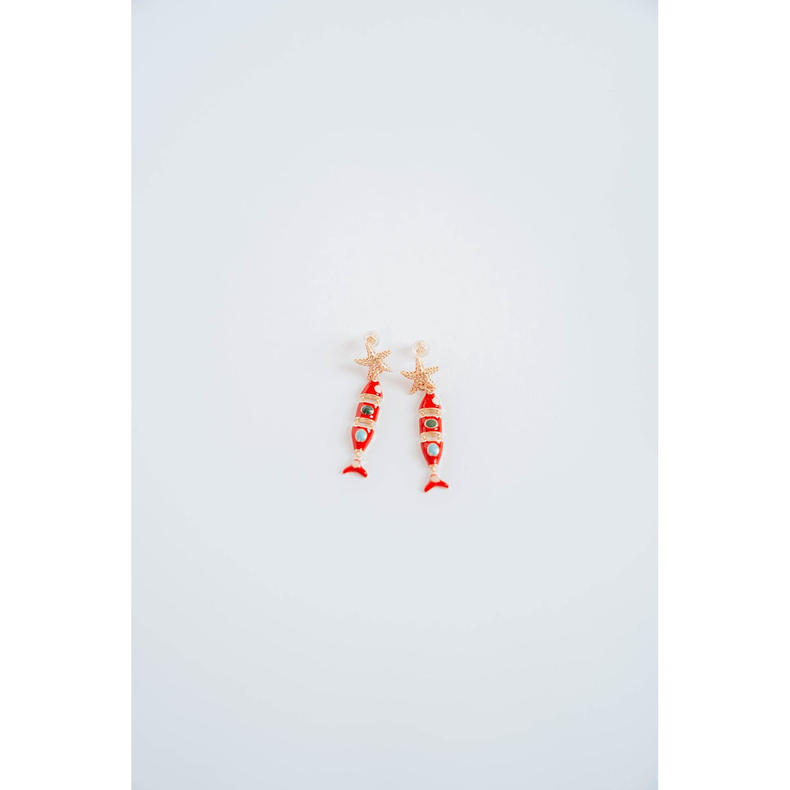 Pair of red and gold fish-shaped earrings on a light gray background