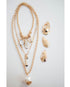 set of three gold layered necklaces with pearl pendants and gold oyster shell pendants on a light background