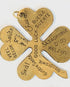 gold/brass four leaf clover charm with "good luck" engraved in different languages on a light background