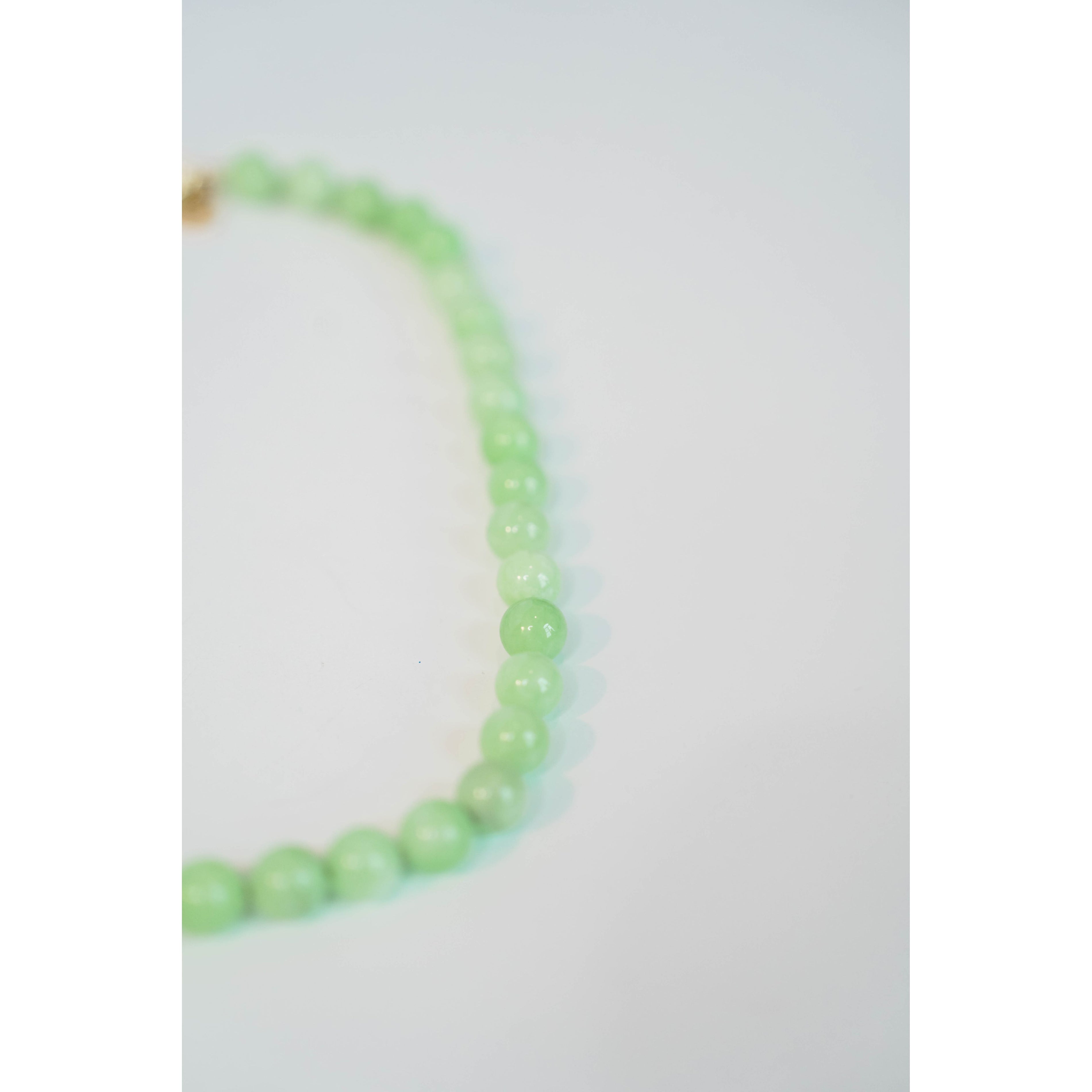 closeup shot of a light green beaded necklace against a light background