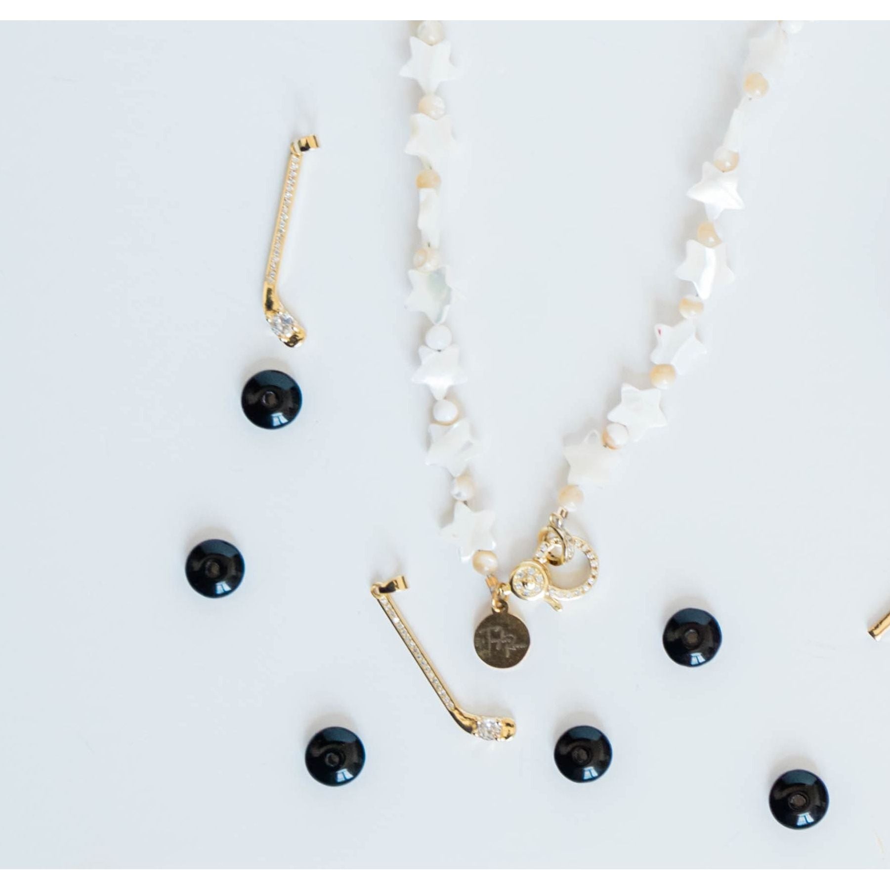 necklace with white star beads placed by gold hockey stick charms with pave detailing