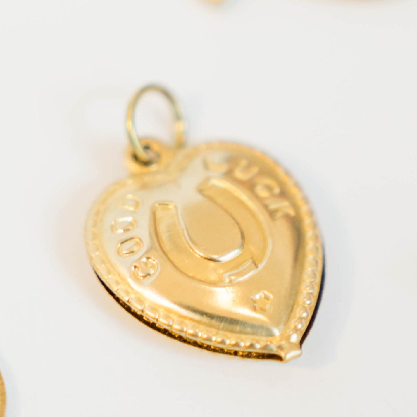 Double-sided gold/brass puffy heart charm with a horseshoe that reads "good luck"