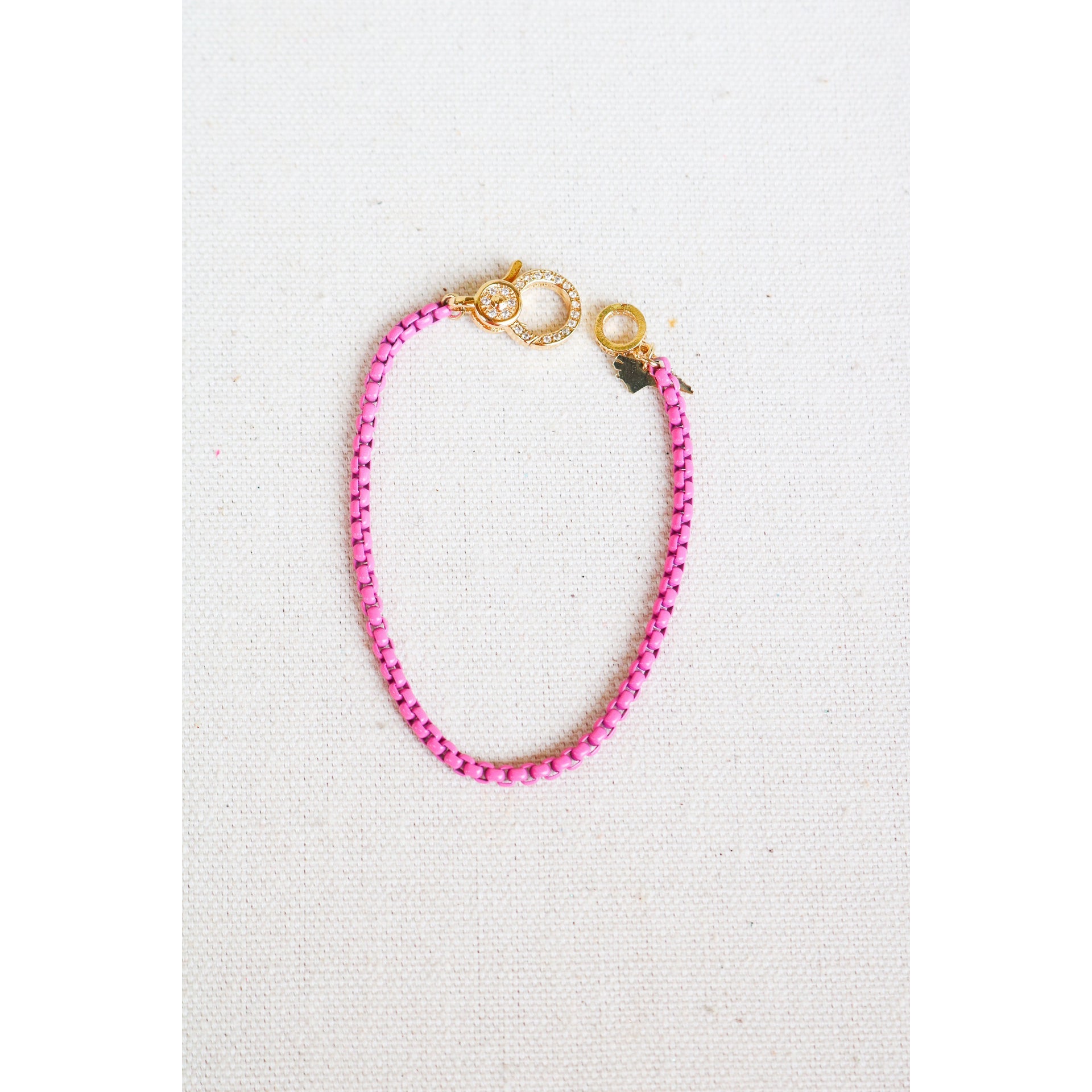 hot pink box chain bracelet with a gold pave lever clasp on a light grey background