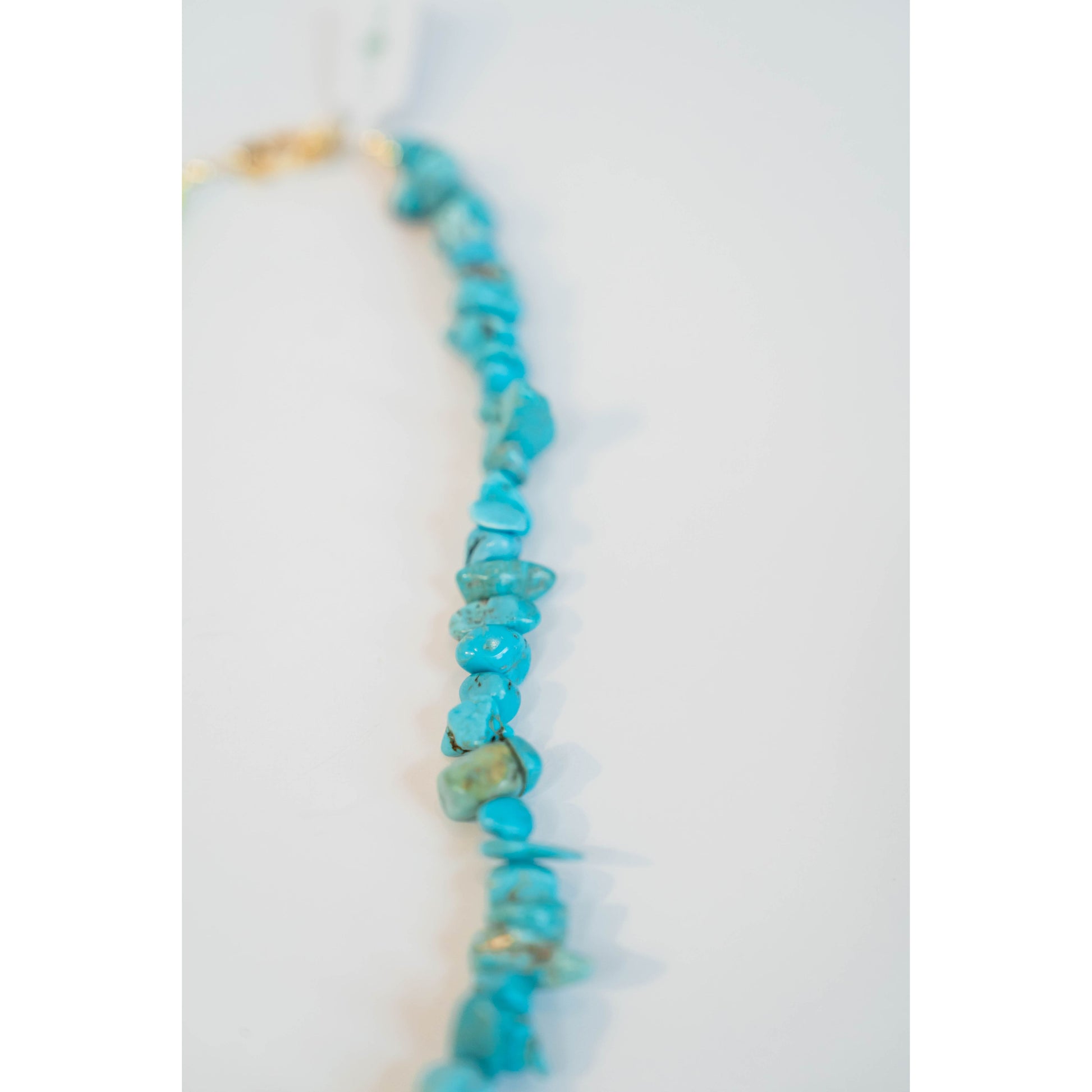 turquoise beaded necklace on a light grey necklace