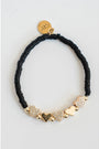 Black beaded bracelet with gold pave heart-shaped charms on a light grey background