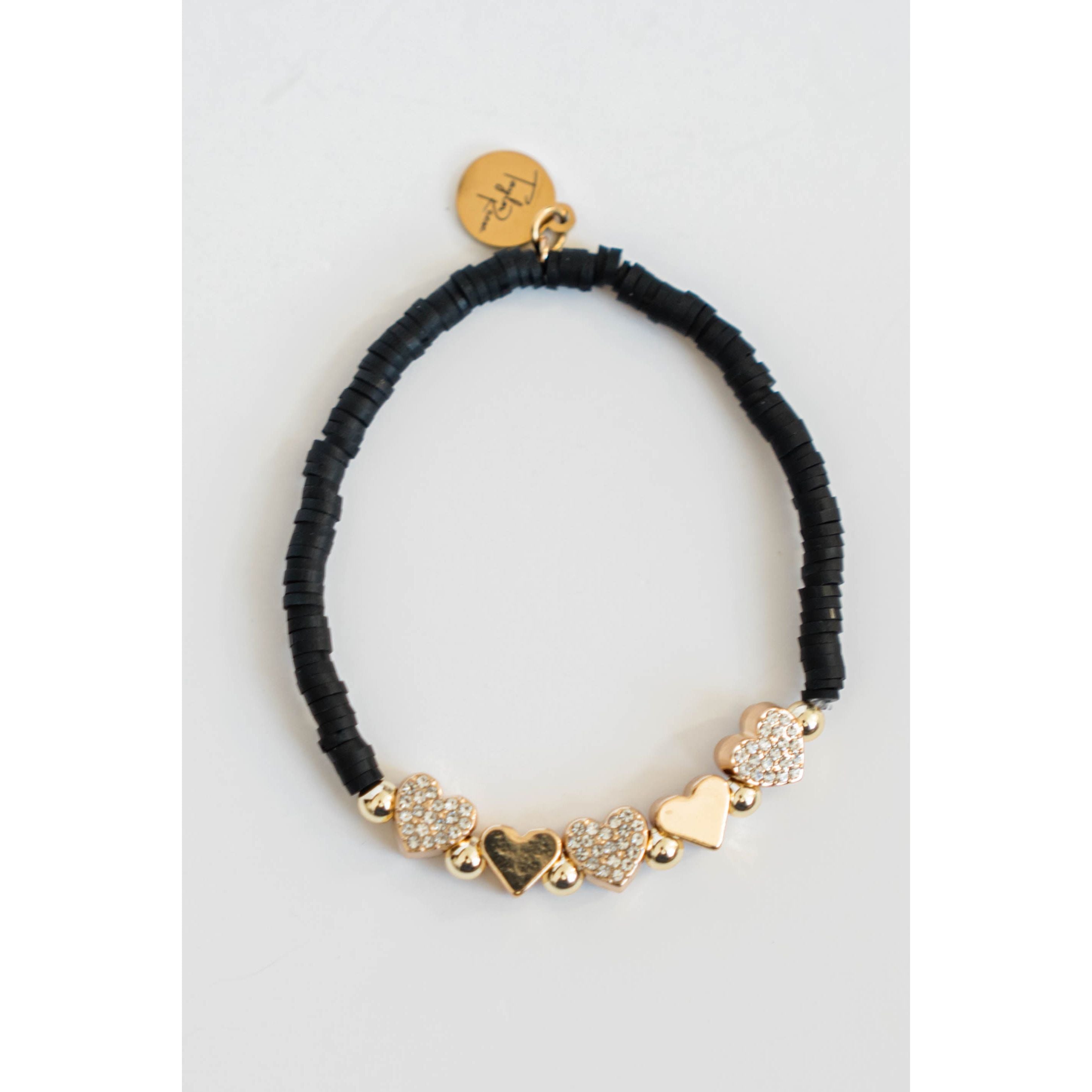 Black beaded bracelet with gold pave heart-shaped charms on a light grey background